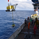 A seismometer being lifted near one of the survey sites.